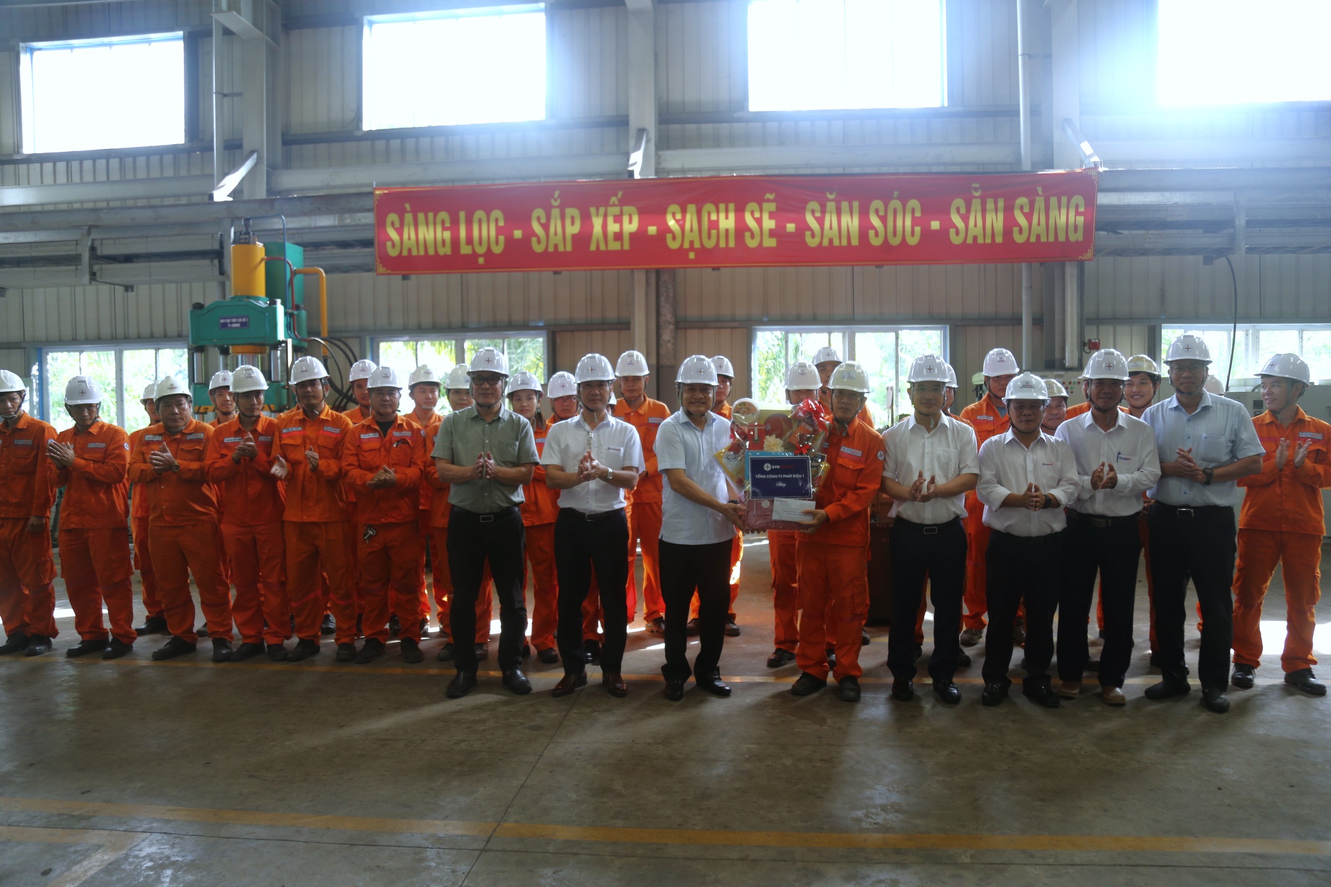 A group of men in white helmets and orange jumpsuits holding a boxDescription automatically generated