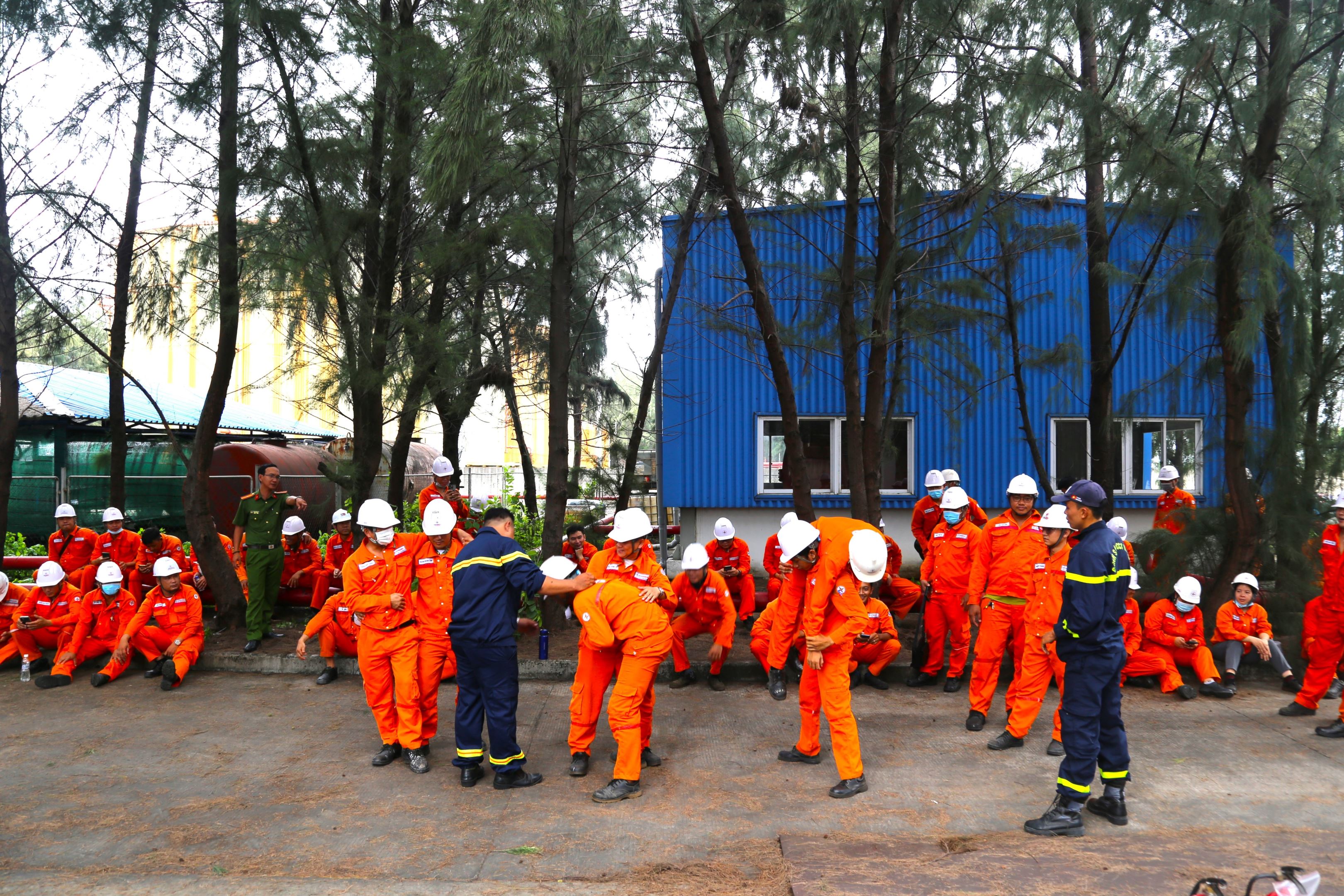 A group of people in orange jumpsuits and white helmetsDescription automatically generated