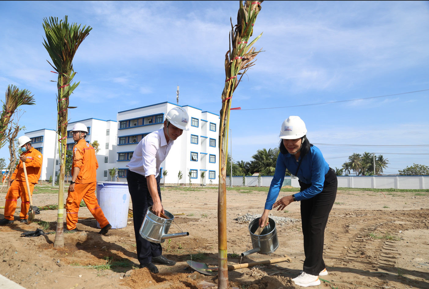 A group of people standing next to a row of palm treesDescription automatically generated